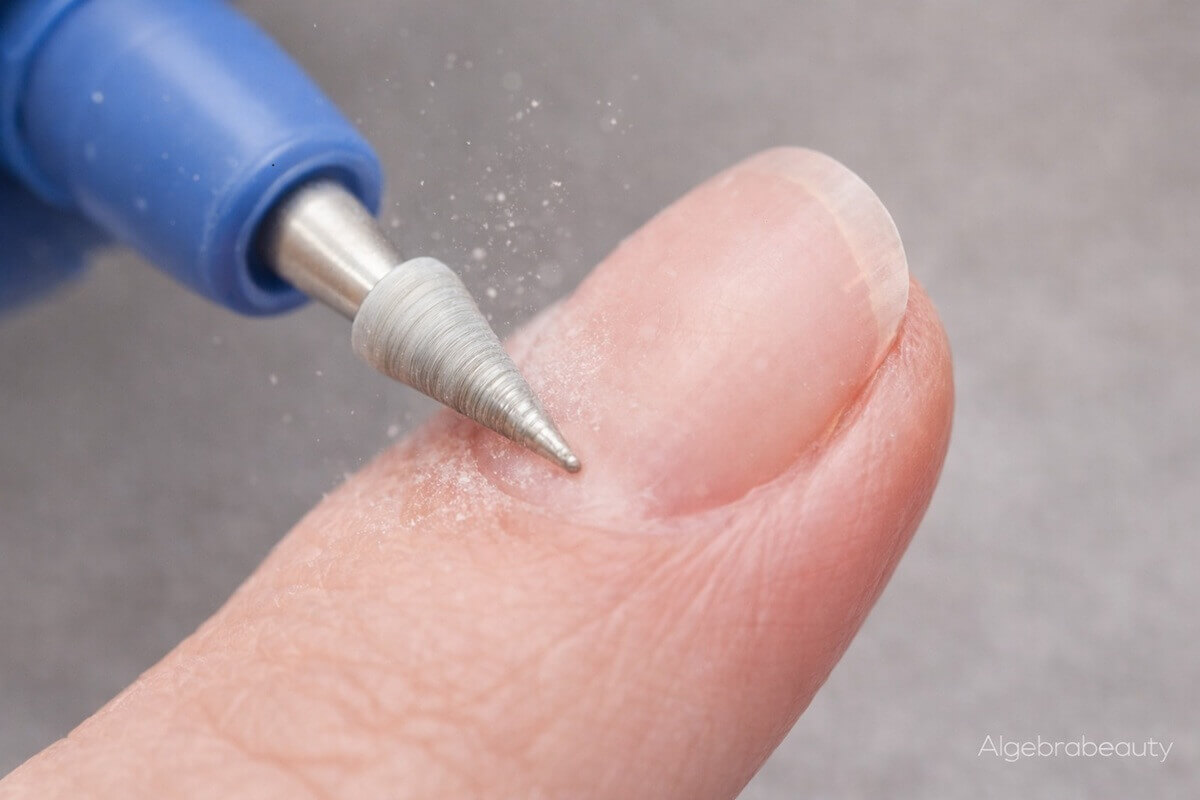 Аппаратный маникюр: аккуратная обработка кутикулы фрезой крупным планом, видна мелкая пыль после обработки