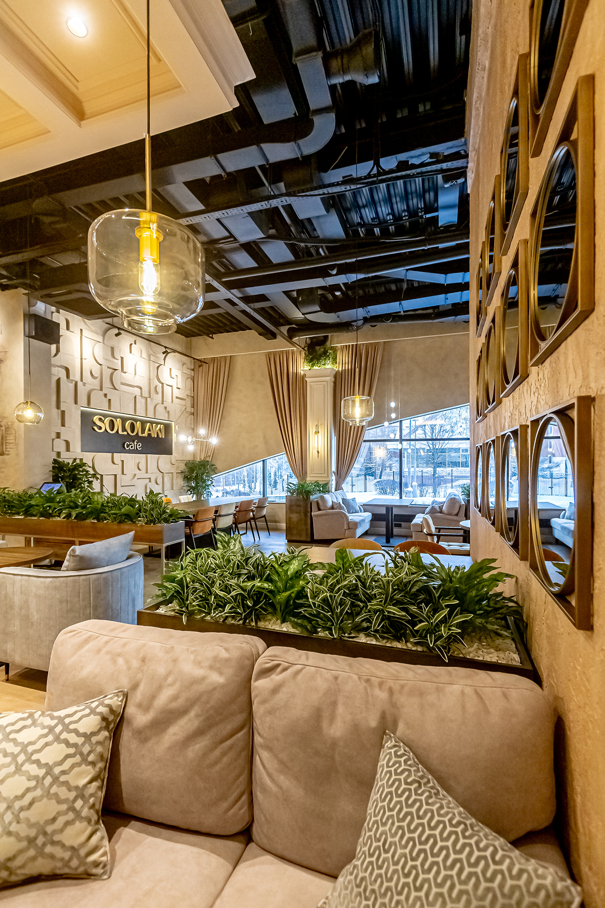 Высокие кашпо с растениями между диванов