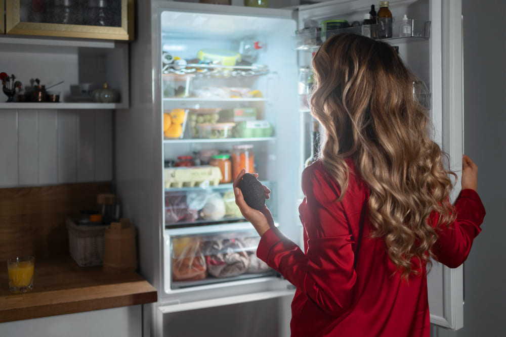 Женщина заглядывает в холодильник