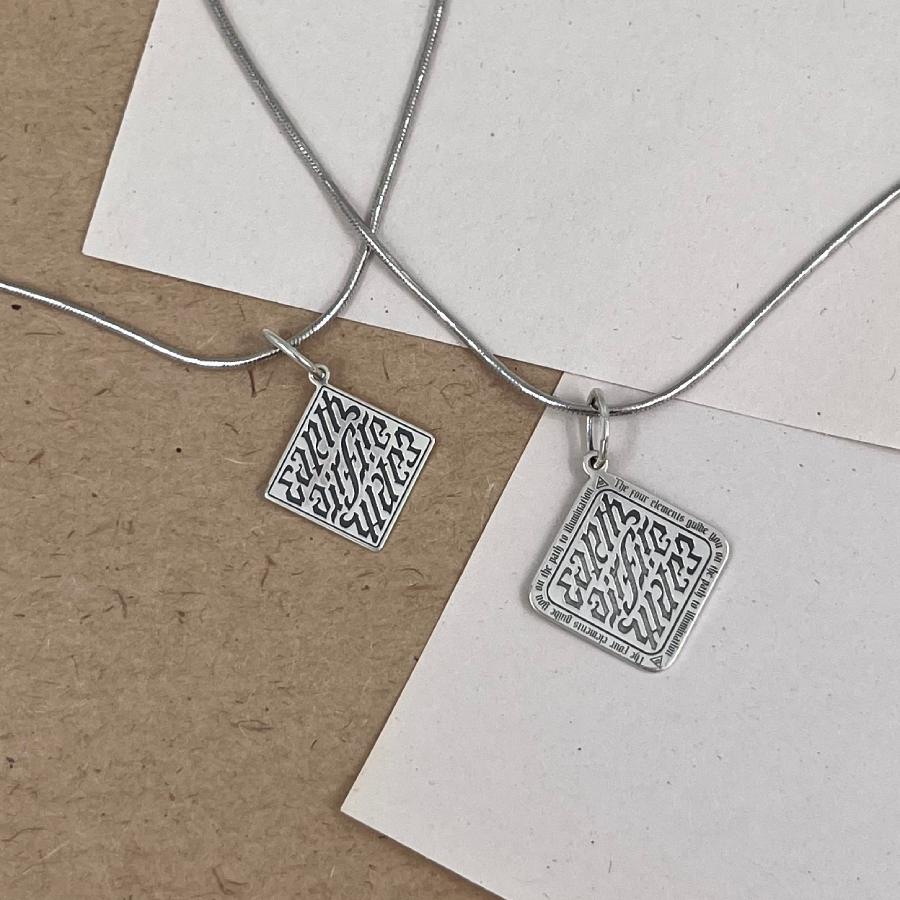 совместное лайф-фото подвесок Ромб иллюминатов 2 фотография двух подвесок Ромб иллюминатов на цепочках из серебра на фоне листков бумаги горчичного и молочного цвета