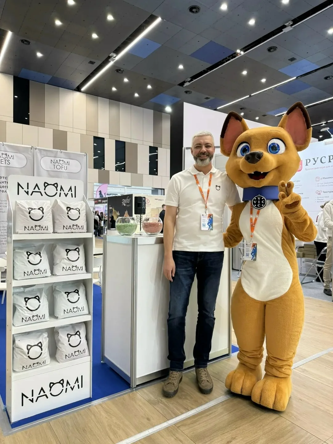 Сотрудник NAOMI PETS с маскотом собаки на стенде выставки