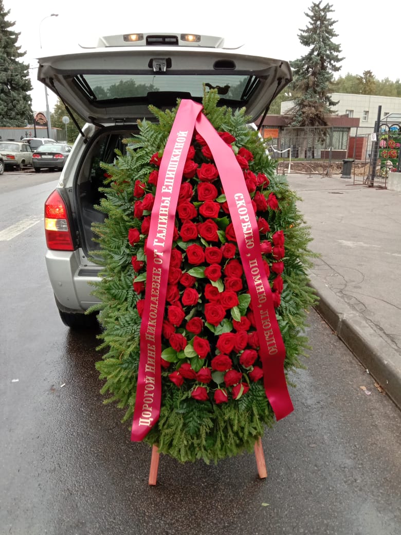 живой венок из роз с красной траурной лентой