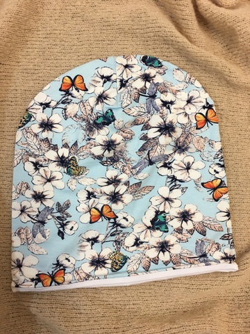 Удлиненная шапочка бини из вискозного трикотажа с цветами, бабочками и стрекозами на светло-голубом фоне.