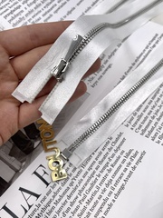 Молния на белой атласной тесьме серебристая