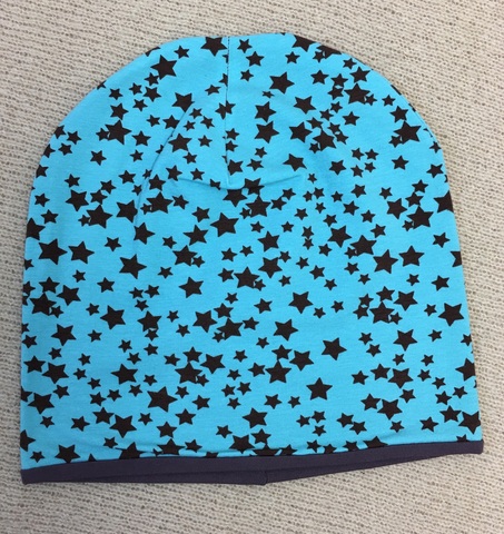 Удлиненная шапочка бини из вискозного трикотажа с мелкими коричневыми звездочками на мятном фоне.
