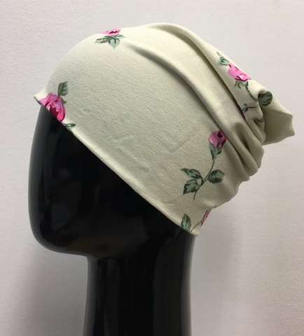 Удлиненная шапочка бини из вискозного трикотажа с розами и листиками на кремовом фоне.