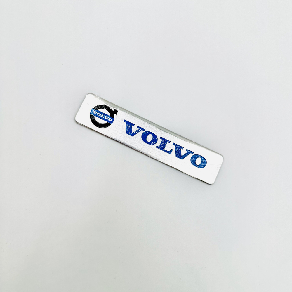 Наклейка Volvo с лого объемная полиурентан (шильдик Вольво, 12х2,5см). Серебристая с синей надписью и лого
