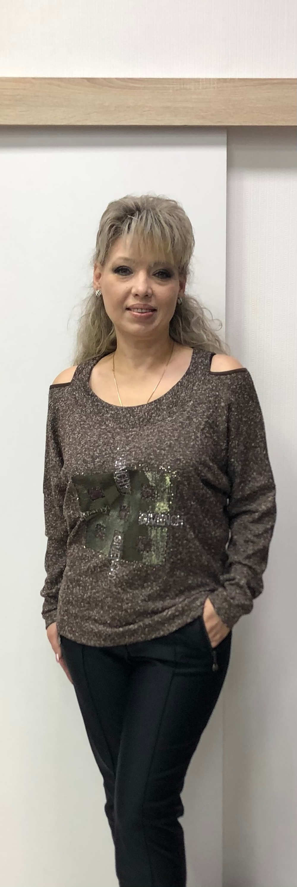 Бежево-коричневый джемпер со стразовой отделкой по груди и вырезами по плечам.