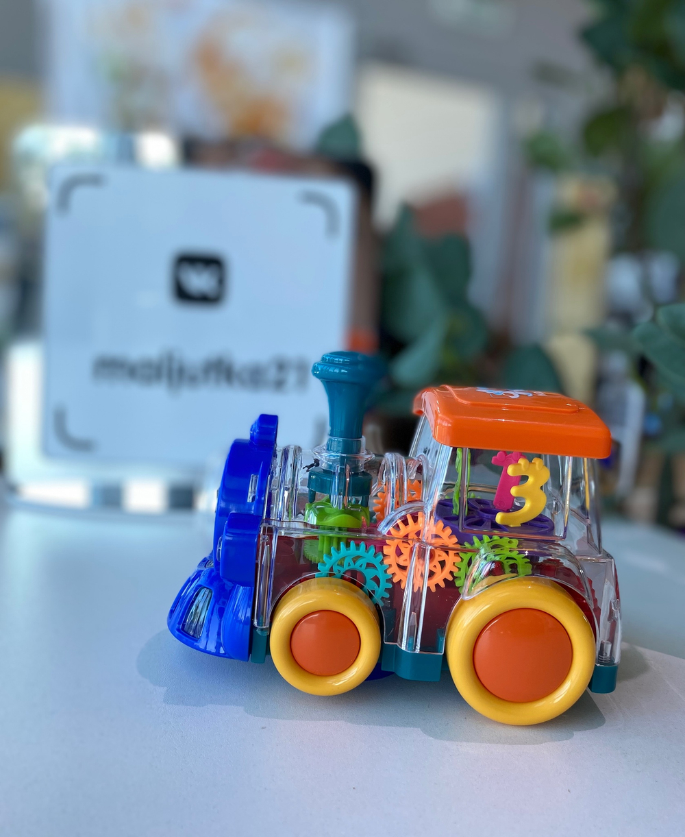 Игрушечный прозрачный паровозик с движущимися шестеренками со световыми и звуковыми эффектами