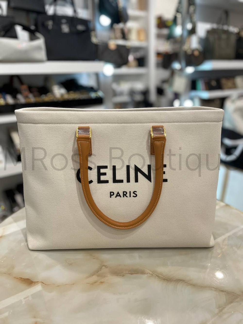 Celine Cabas Drawstring premium women's shopper bag crafted from canvas with brown calfskin inserts. Discreet beach bag with black Celine lettering on the front, brown leather handles and an inside zip pocket.