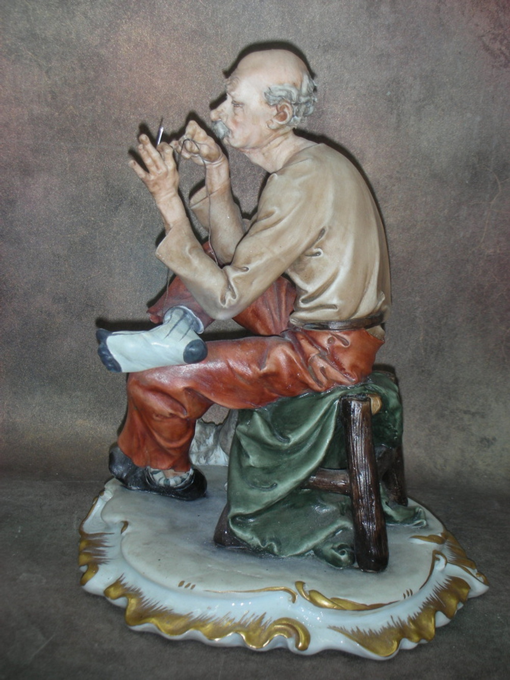 Статуэтка. Фарфор. Мужчина, зашивающий носок. Capodimonte. Италия