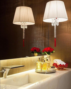 Изысканное люстра Baccarat с белым плиссированным абажуром, хрустальной ножкой и акцентной красной кистью.