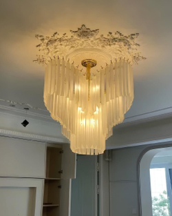 Изысканная каскадная люстра с вытянутыми стеклянными элементами и декоративной потолочной розеткой.