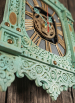 Детальный вид мятных резных часов-наличника WOODandROOT, слоистая покраска подчёркивает фактуру орнаментов и создаёт глубокий северный оттенок.
