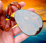 Янтарный кулон на ладони, вид с обратной стороны