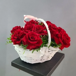Композиция из 15 красных роз в плетеной корзине.