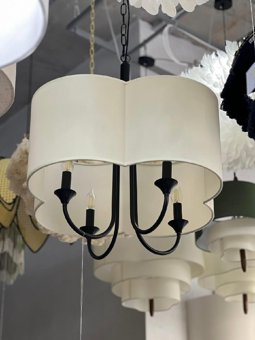 Элегантная люстра с текстильным абажуром в светлом оттенке и черным металлическим основанием.