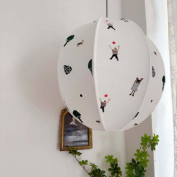 Нежный подвесной светильник в виде круглого абажура с минималистичными рисунками людей и деревьев.