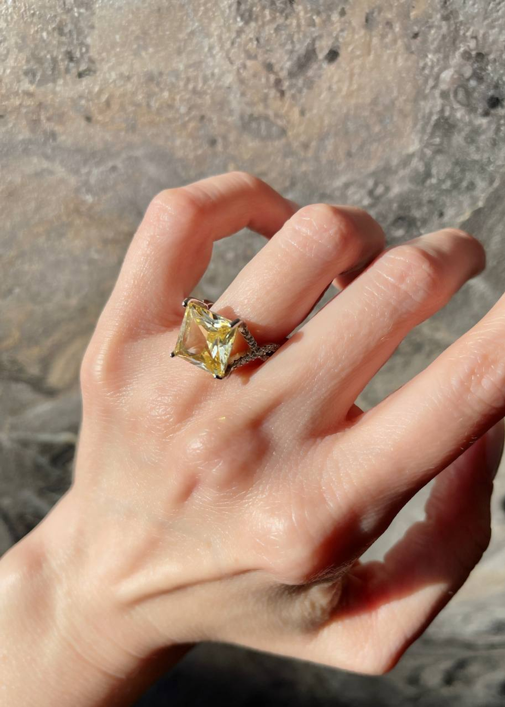 Серебряное кольцо с желтым фианитом квадратной формы и белыми микроцирконами на шинке добавит нотку элегантности в ваш образ. Носите его со стилем Casual или строгим деловым костюмом – изделие придаст яркости любому гардеробу. Украшение произведено из гипоаллергенного и высокопрочного серебра 925-й пробы, следовательно, не причинит дискомфорта. Купить кольцо с желтым фианитом квадратной формы и белыми микроцирконами на шинке можно в нашем ювелирном магазине по доступной цене. Изделие доставляется как по Москве, так и всей территории РФ.