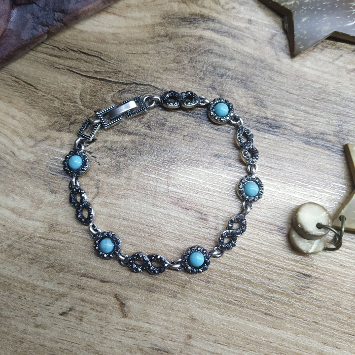 Браслет Vogue Восьмерка стразы графитовые круг бусина под бирюзу металл серебристый на красном бархате