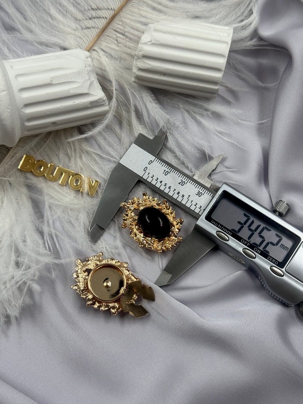 Накладка на пуговицу золотистая с ажурным (неровным) краем и черным камнем