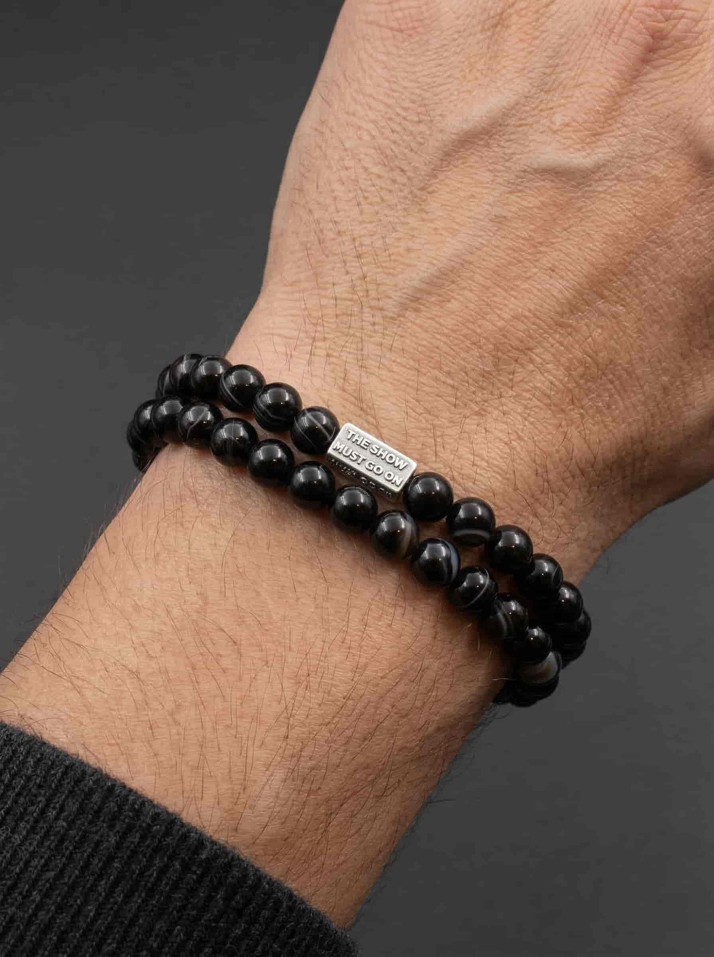 Фото серебряного шарма бусины The Show must go on в браслете из натуральных камней на руке