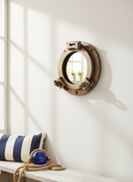 WOODandROOT зеркало-иллюминатор в морском интерьере с подушкой в полоску и канатом, тёплый солнечный свет и лёгкая навигационная атмосфера.