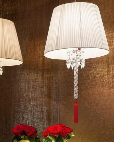 Изысканное люстра Baccarat с белым плиссированным абажуром, хрустальной ножкой и акцентной красной кистью.