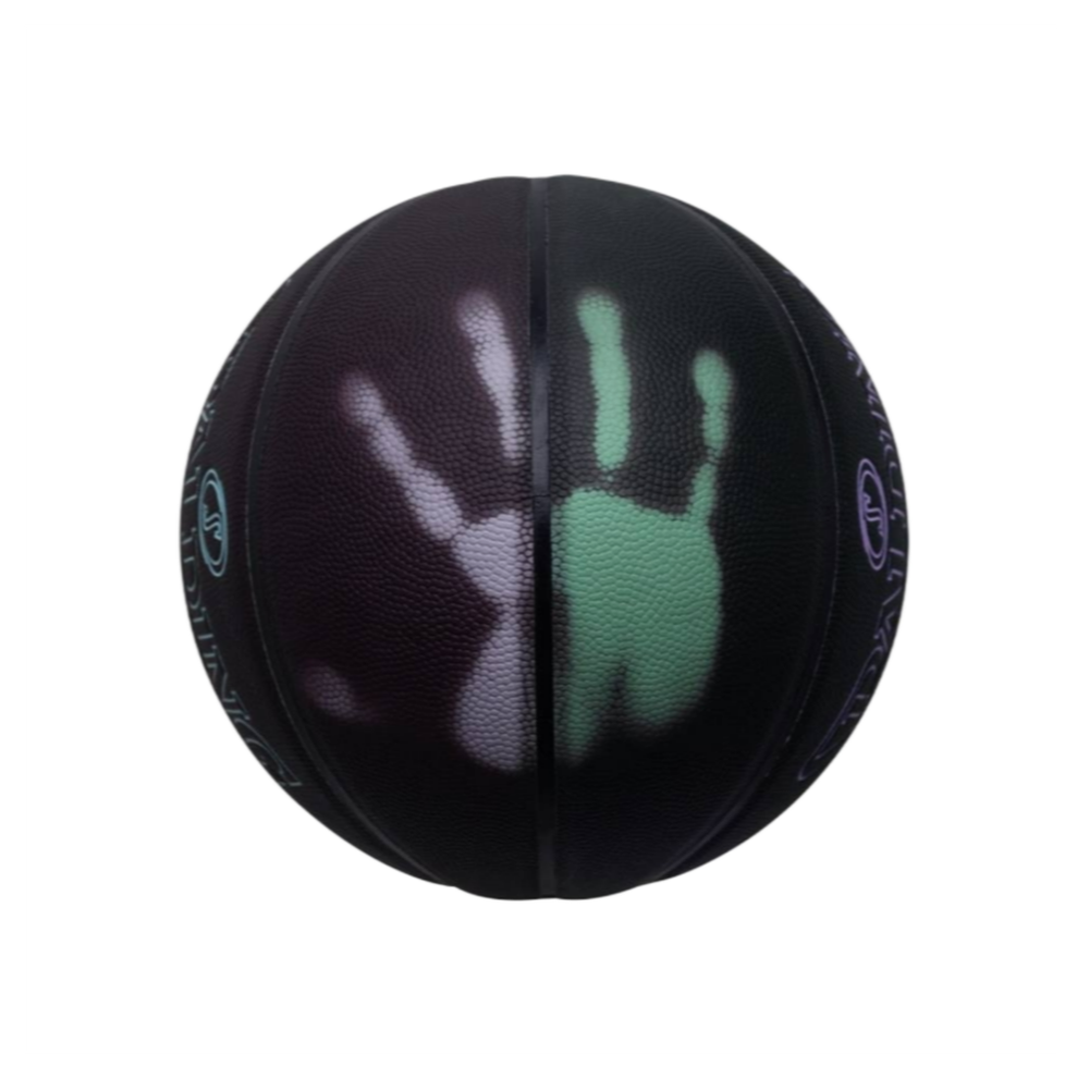 Черный баскетбольный мяч Spalding SPIRIT Color Switch размера 7 с фиолетово-зеленым логотипом, термохромное покрытие на светлом фоне.