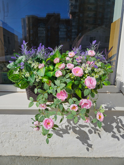 Розы лиловые с зеленью в длинном кашпо ротанг