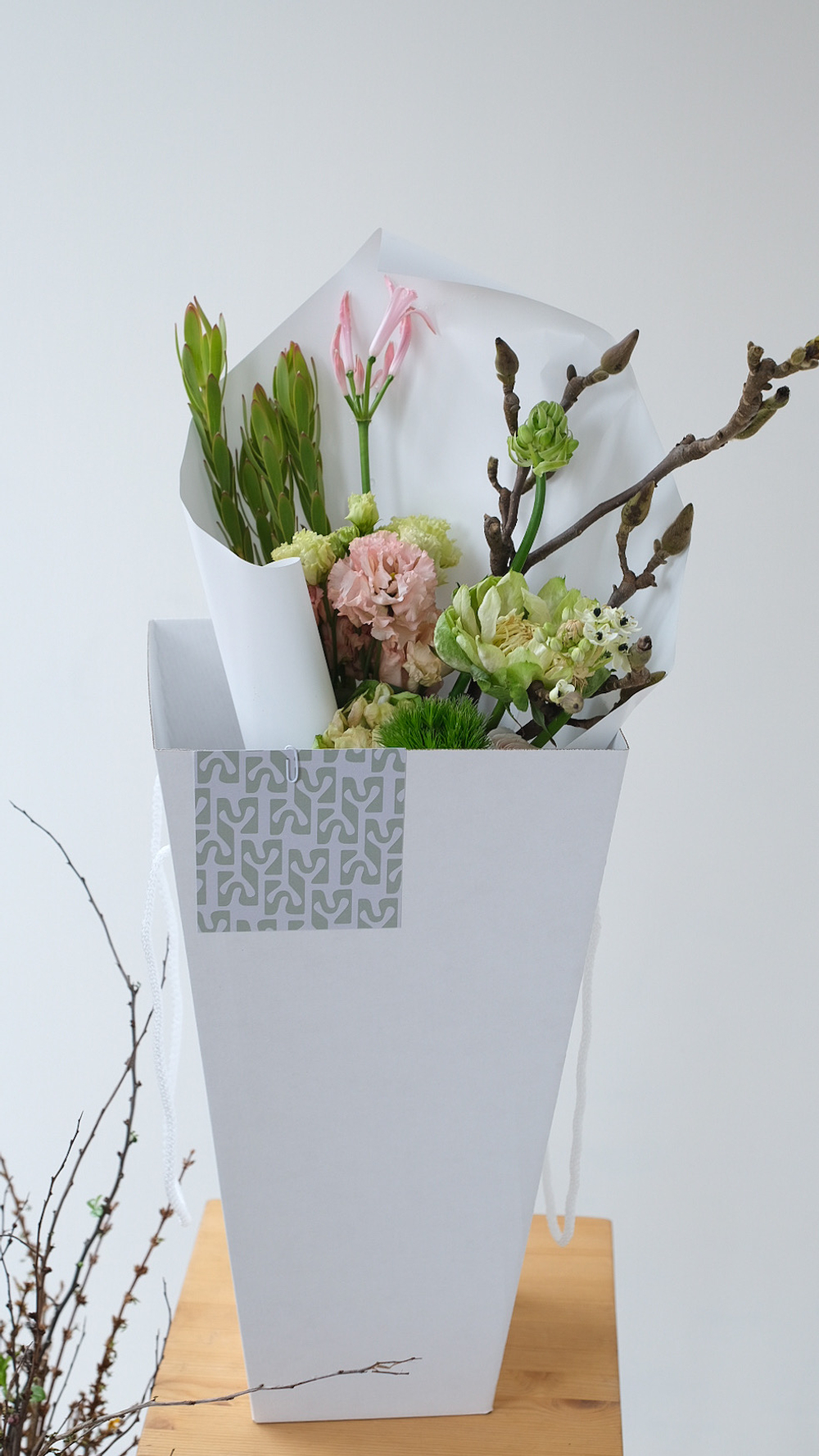 Букет с ветками магнолии, розами Вегги, нерине, орнитогалумом и ранункулюсами