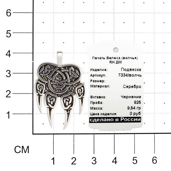 Фото подвески печать Велеса волчья лапа из серебра на размерной сетке в масштабе с ювелирной биркой.