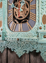 Фрагмент мятных резных часов-наличника WOODandROOT, видна слоистая покраска и аккуратные золотистые акценты, подчёркивающие глубину орнамента.