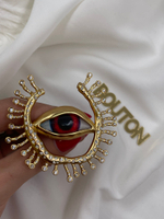 Брошь Скиап. золотистая в форме глаза с подковой из ресниц со стразами красный