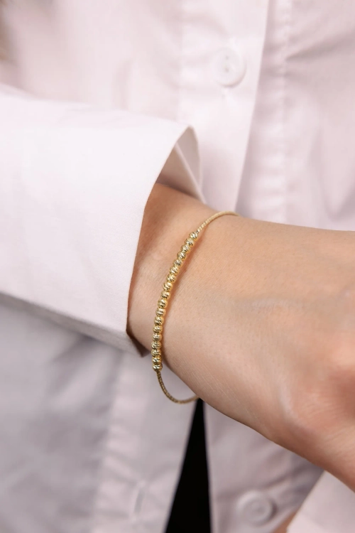 Жесткий браслет с шарами и алмазными гранями в золочении