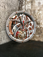 Настенные часы WOODandROOT Automaton 1277 Tourbillon с кинетическими шестерёнками у текстурной бетонной стены в индустриальном интерьере.