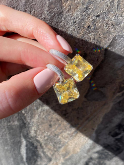 Спокойный и благородный цвет кристалла побуждает купить серьги с микро фианитами белого цвета и желтым центральным камнем в виде квадрата. С ними можно создать десятки вечерних и повседневных образов. Чтобы акцентировать внимание на квадратных серьгах из серебра 925-й пробы с желтым фианитом, можно дополнить их кольцом или кулоном с большим камнем в том же стиле или оттенке. Особенно советуем приобрести изделия девушкам с карими глазами. Благодаря скромным на первый взгляд серебряным украшениям цвет глаз станет еще выразительней.  Заказать серьги из серебра с желтыми фианитами вы можете в нашем интернет-магазине по демократичной цене. Доставка ювелирного изделия возможна как по столице, так и в любую точку страны.