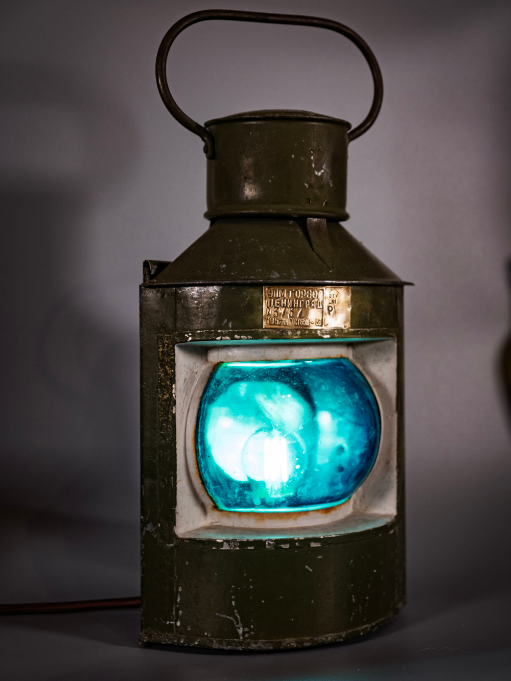 Корабельный навигационный фонарь WOODandROOT 1957 года с мягким сине-зелёным свечением, сохранивший патину и оригинальный металлический корпус.
