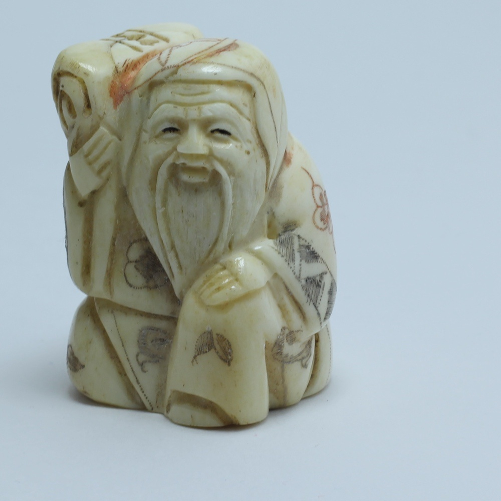 Нэцкэ Фукурокудзю сядящий со свертком на плече