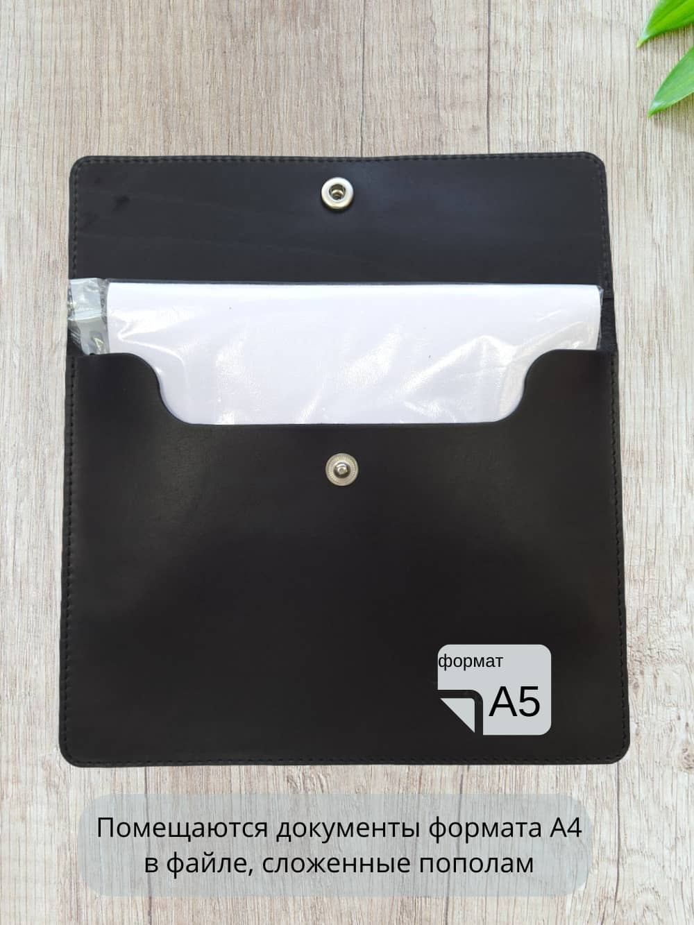 Фотография папки формата А5 из натуральной кожи чёрного цвета в раскрытом виде с примером размещения документов А4