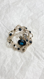 Брошь абстракционные золотистые линии в круг со светло-серыми и синими кристаллами