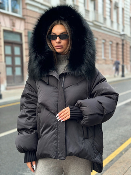 Черный пуховик с удлиненной спинкой и мехом енота