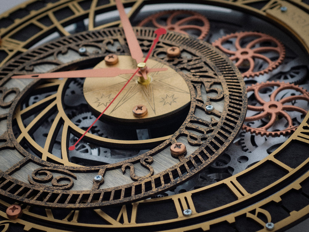 Крупный план WOODandROOT Automaton Prague, вращающиеся латунные шестерёнки и медные стрелки на фоне чёрного циферблата
