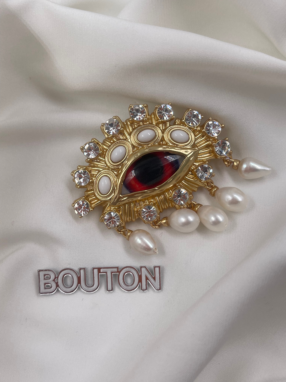 Брошь Скиапар. золотистая в форме красного глаза с жемчугом и стразами