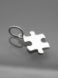 Реальная фотография подвески пазл из серебра на темном фоне