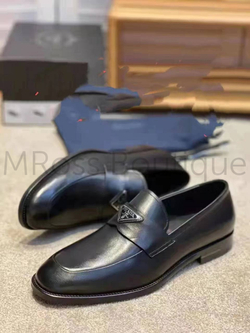 Традиционно используемая в изысканной классической обуви, матовая кожа является частью культовых материалов Prada с 90-х годов. Здесь он используется для зауженных лоферов, украшенных спереди эмалированным металлическим треугольным логотипом.