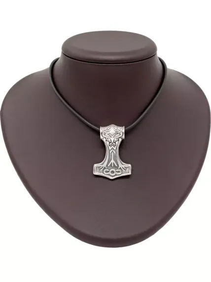 Фото подвески Мьельнир из серебра с руной Альгиз на коричневом постаменте.