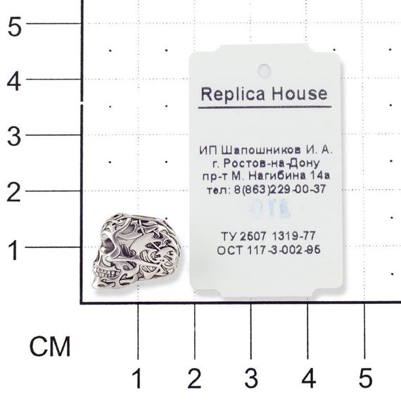 Изображение темлячной бусины из серебра Tribal skull на размерной сетке в масштабе с ювелирной биркой.