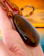 Янтарный кулон на ладони, вид сбоку