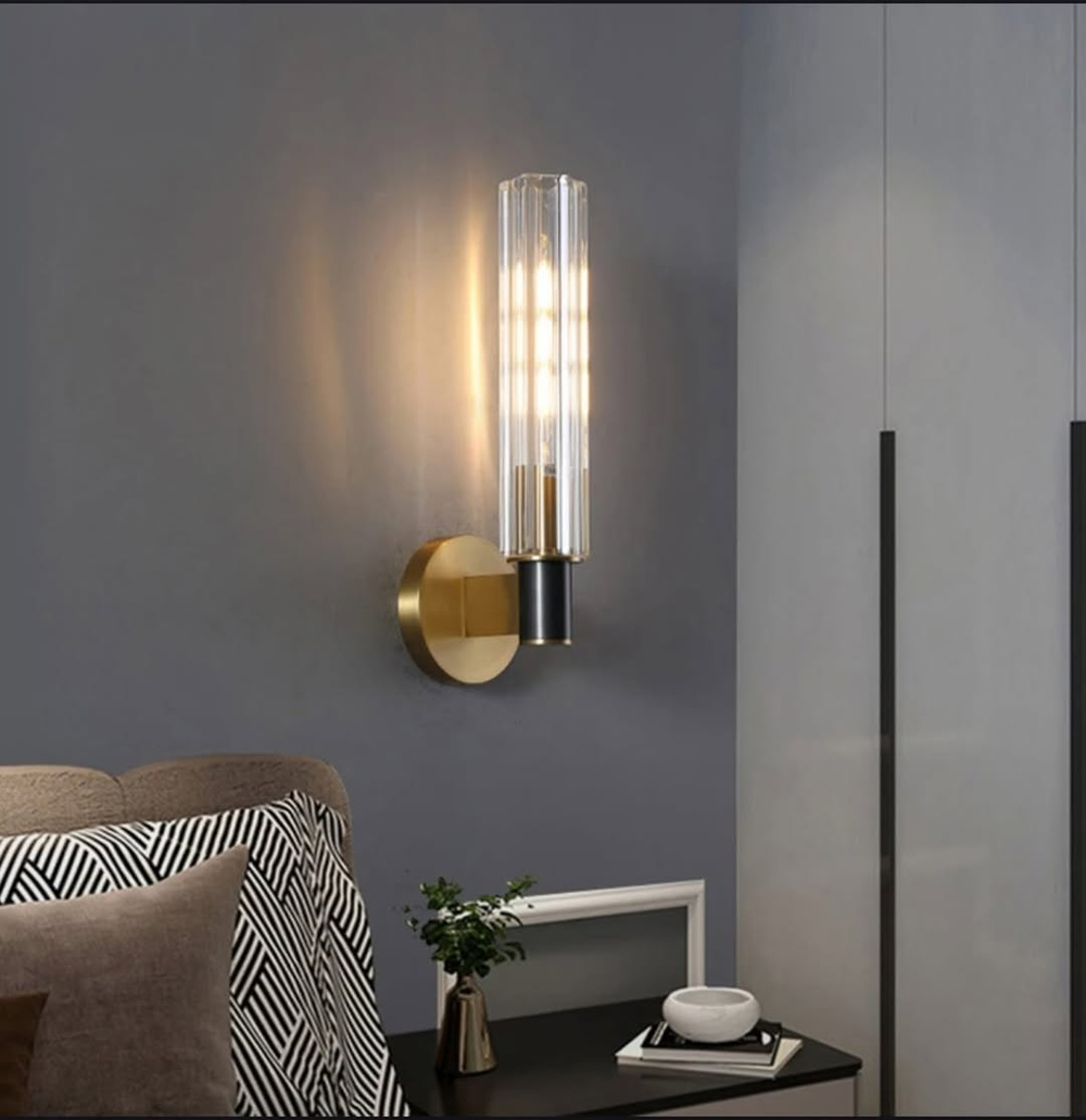 Элегантное настенное бра с вытянутым хрустальным плафоном и металлическим корпусом в тёплом золотом оттенке.